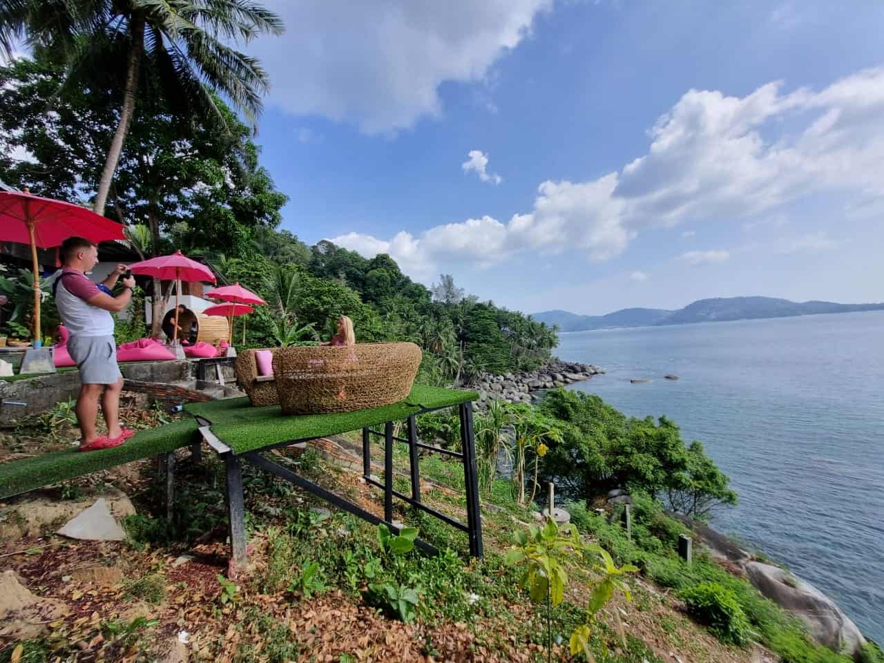 Tropical hillside with ocean view and pink umbrellas.