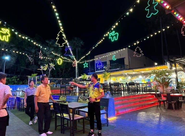 Outdoor restaurant with colorful lights and people.