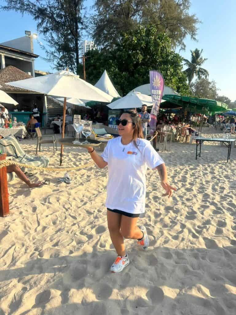Server carrying drinks on a sunny beach.