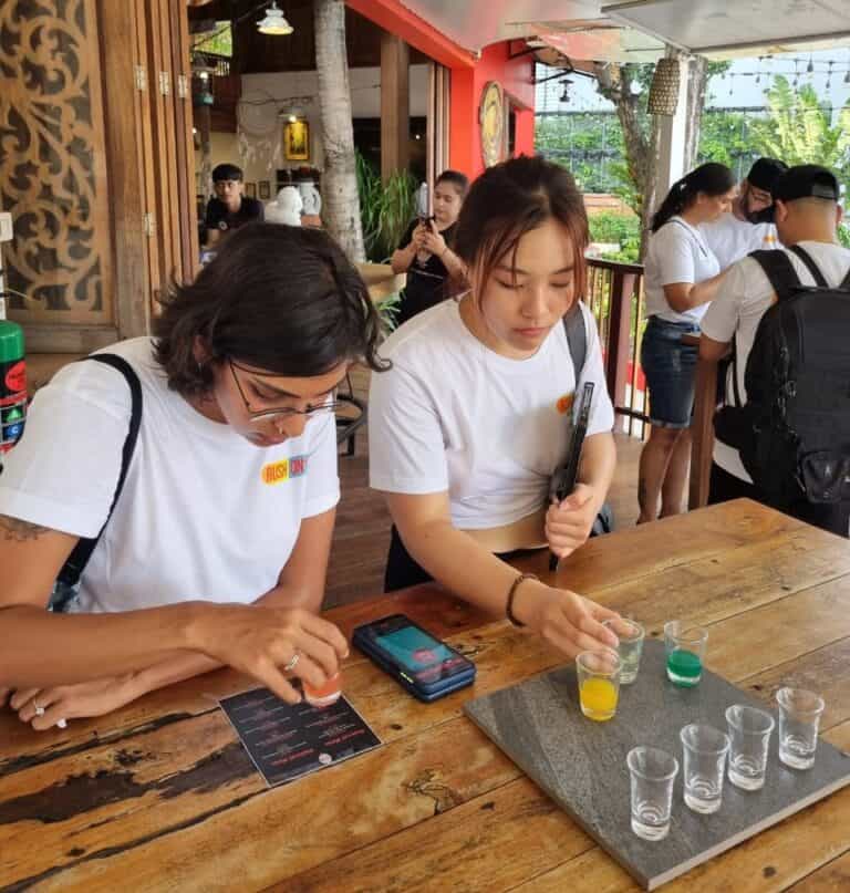 People tasting colorful drinks at wooden table.