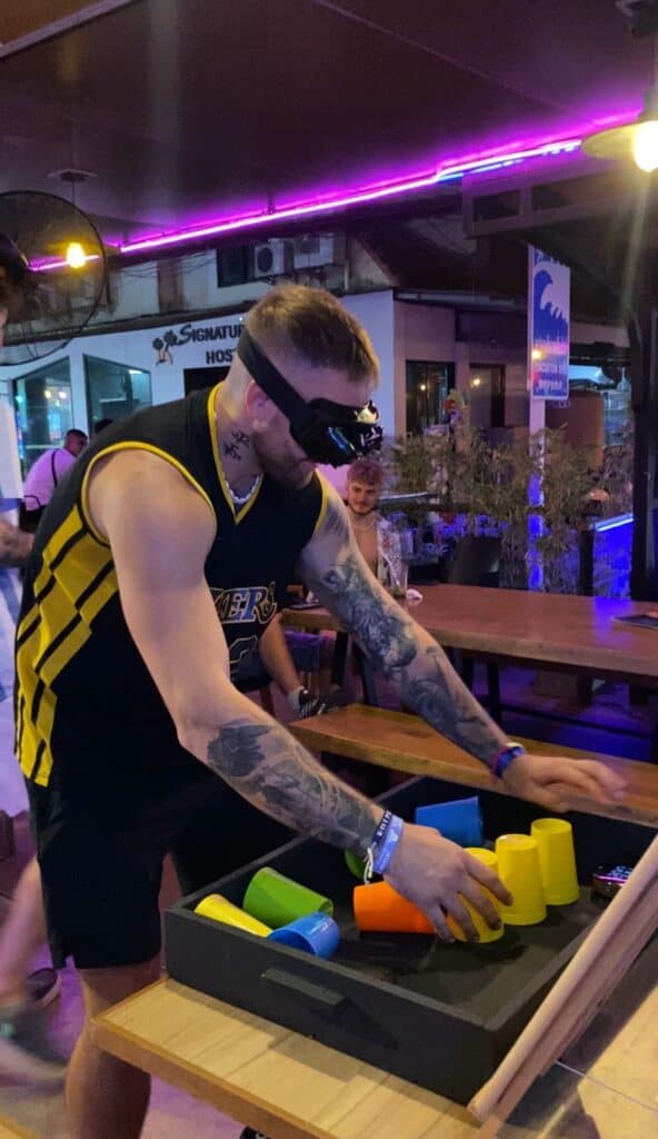Man playing colorful cup stacking game blindfolded.