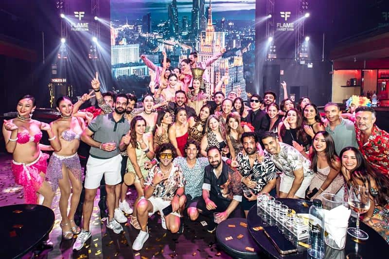 Large group celebrating at a nightclub with dancers.