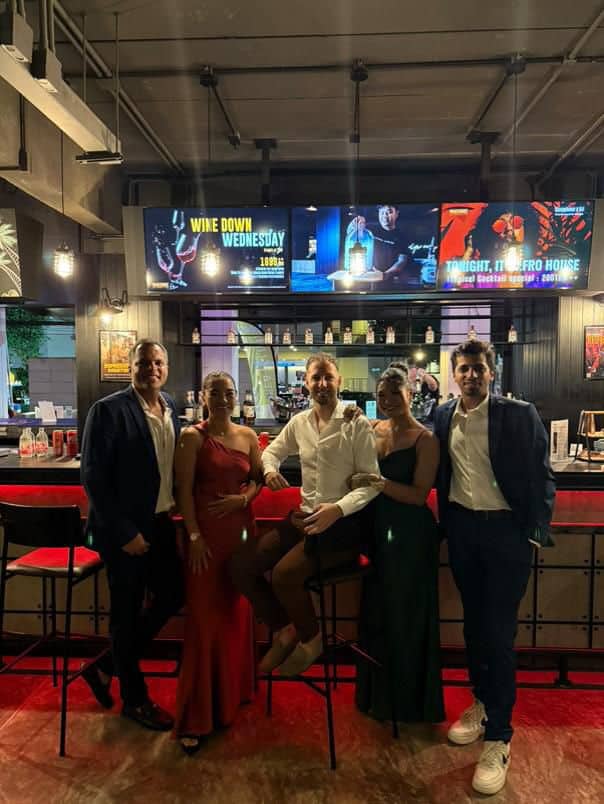 Five people posing at a stylish bar.